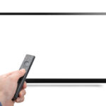 Mockup tv and hand with modern remote control from an online media box isolated on white background. 8k 4k TV with remote control in hand mock up. White blank screen monitor mock-up
